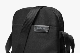 Bellroy City Pouch in Melbourne Black up close, highlighting the finely woven material, black strap and logo label on a white background.