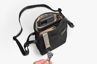 Bellroy City open bag in black with keys, smartphone, wallet and pen visible inside; with adjustable shoulder strap and thin inner lining.