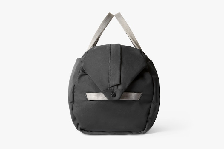 Bellroy Classic Weekender 45L bag in slate black with light gray handles, ribbed texture and button-operated flap on a white background.