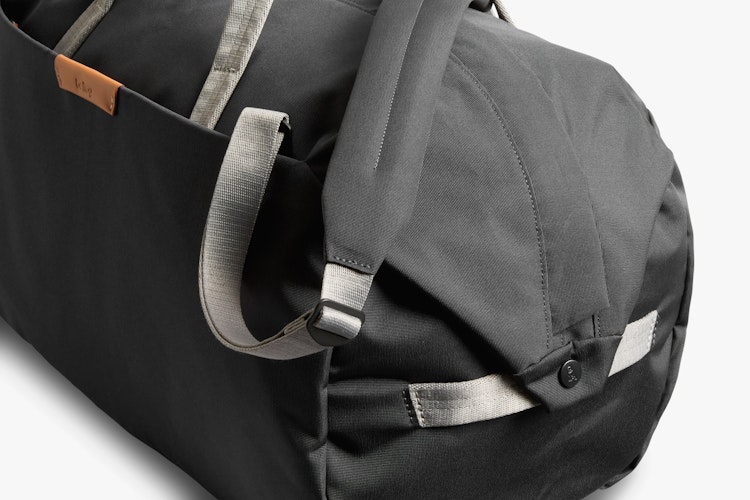 Close-up of the Bellroy Classic Weekender 45L Duffel Bag featuring black fabric, slate gray straps, brown leather trim, and riveted stitching.
