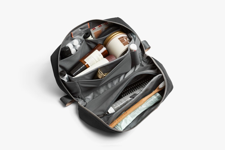 Bellroy Toiletry Kit Plus in slate Ribba fabric, shown open with items organized in compartments, on a white background.