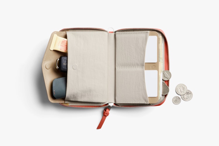 Open Bellroy Folio Wallet in blood orange leather with RFID protection, displaying organized contents and coins on a white surface.