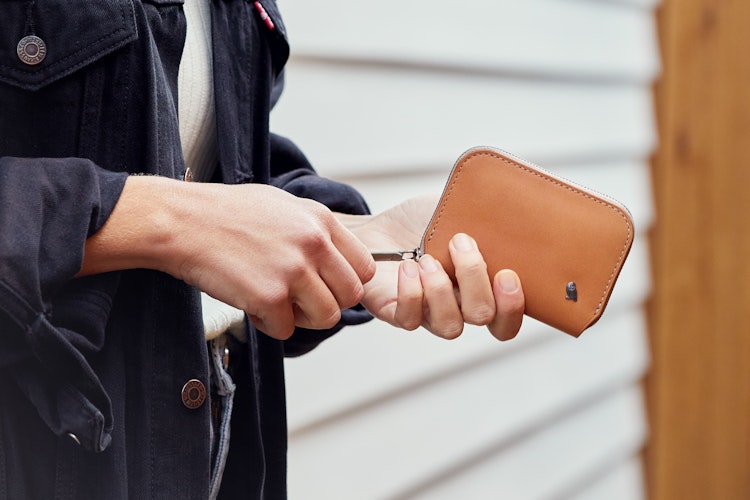 Opened Bellroy Folio Mini RFID wallet made of black leather with organized compartments for cash, cards and documents on a white background.